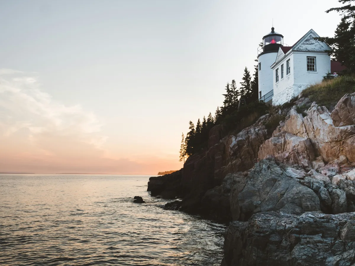Bass Harbor Head Lighthouse above the rocky Maine coastline in warm evening light