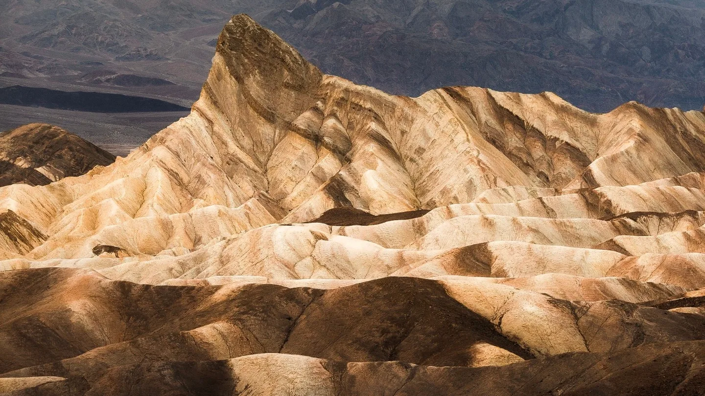 Zabriskie Point badlands and Manly Beacon in warm low-angle light beneath a colorful desert sky