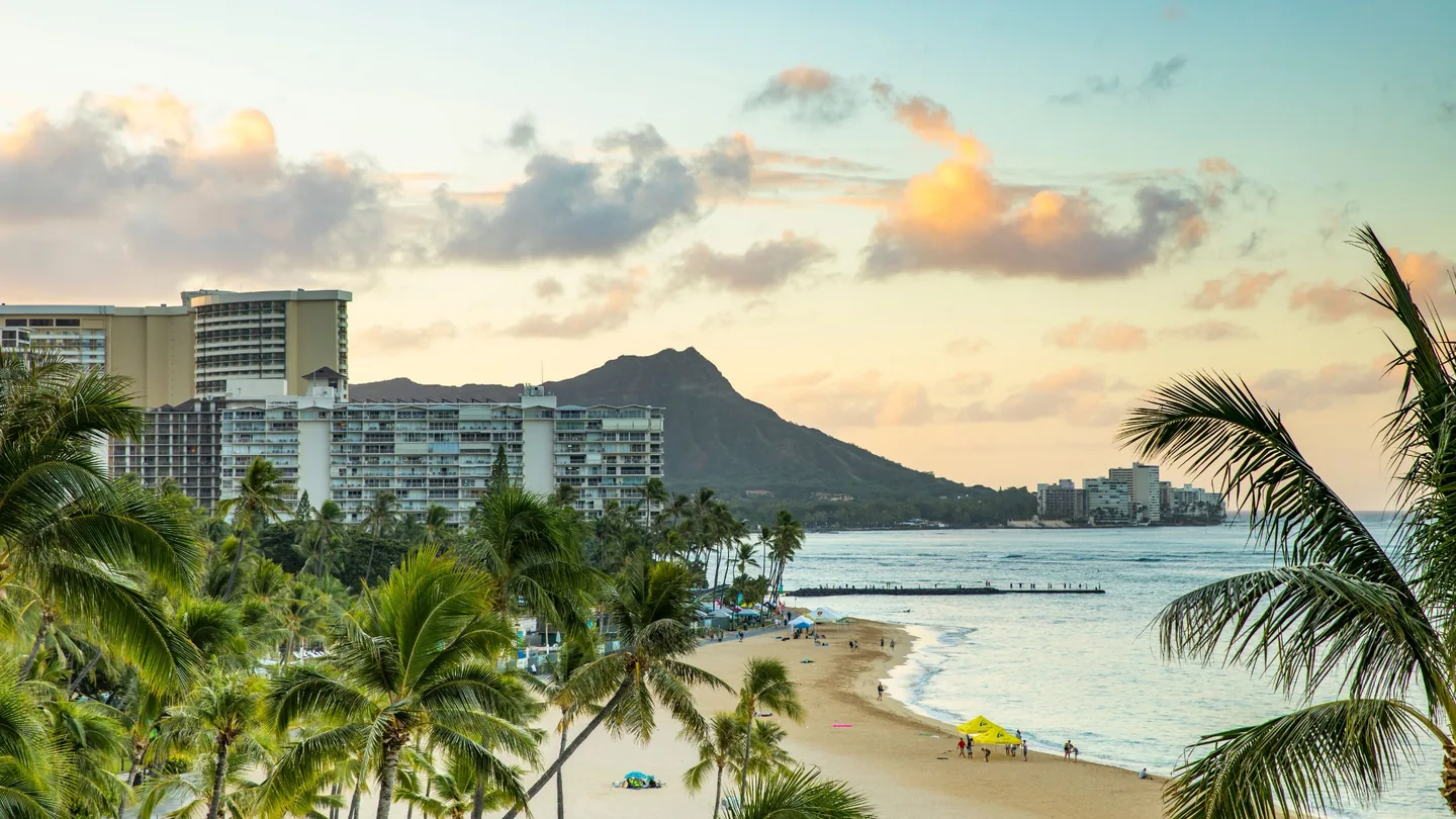 Waikīkī Beach, palm trees and Diamond Head beneath warm tropical evening clouds in Honolulu
