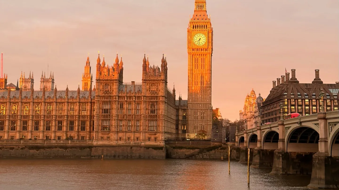 Big Ben and the Houses of Parliament beside the Thames in warm golden-hour light