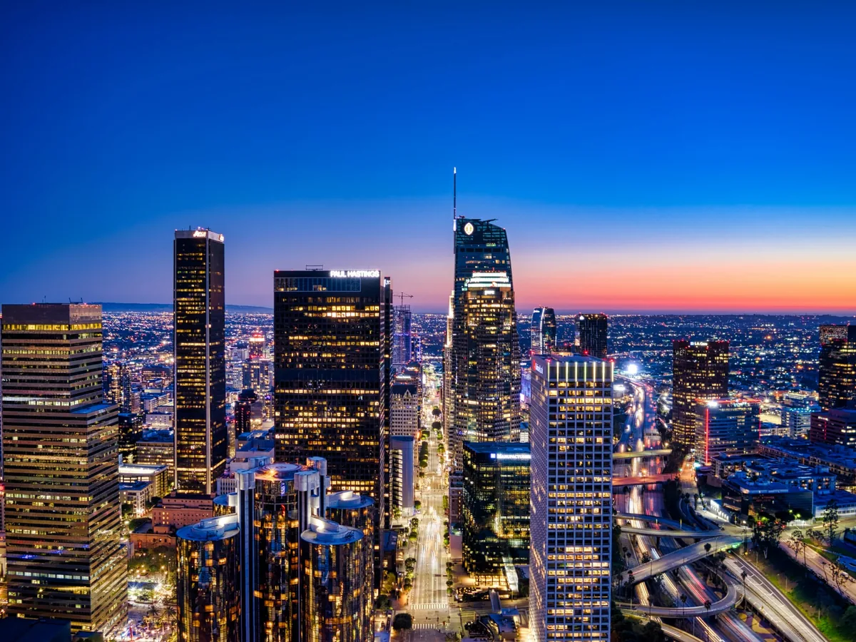 Downtown Los Angeles skyline illuminated during blue hour with a warm horizon glow