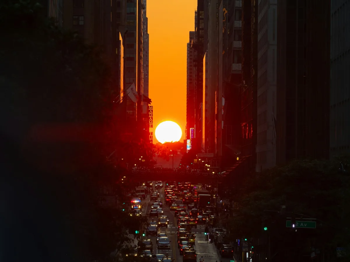 Setting sun aligned between Manhattan skyscrapers above heavy New York City traffic