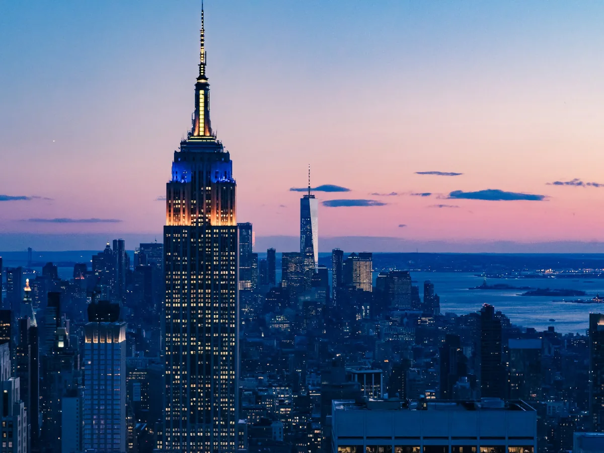Empire State Building illuminated above Manhattan during blue hour with a pink horizon