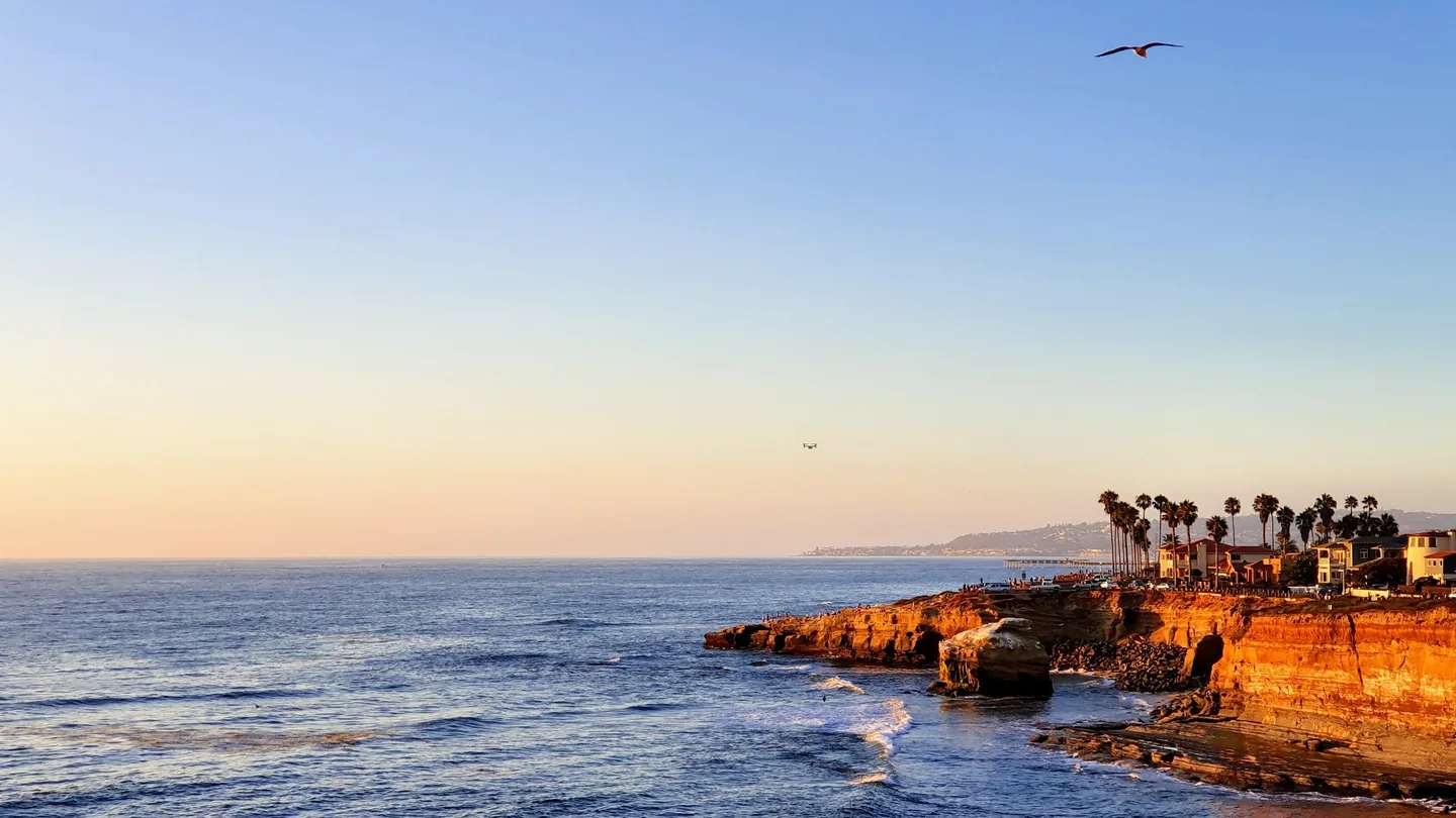 Warm evening sunlight illuminating Sunset Cliffs above the Pacific Ocean in San Diego