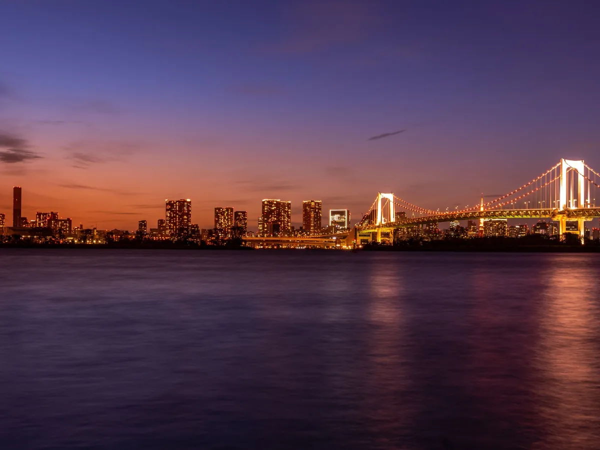 Rainbow Bridge and Tokyo waterfront illuminated above Tokyo Bay during blue hour