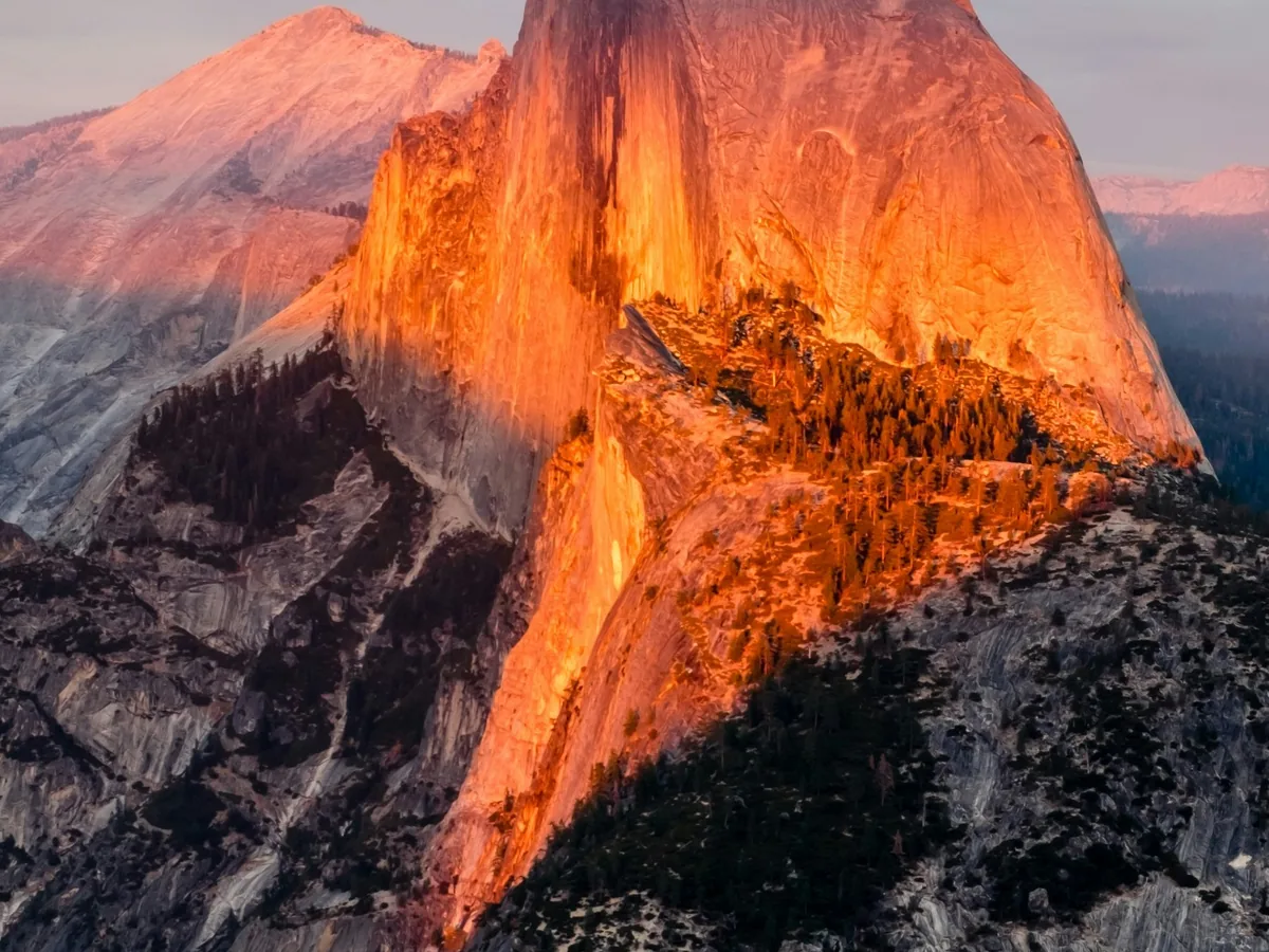 Half Dome illuminated by warm directional sunlight above shadowed Yosemite terrain